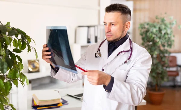 Caucasian Man Doctor Sitting Table His Office Looking Roentgenogram — Stock fotografie