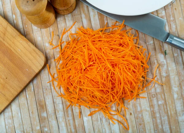 Pile of fresh shredded carrot on top of table. Dish ingredient.