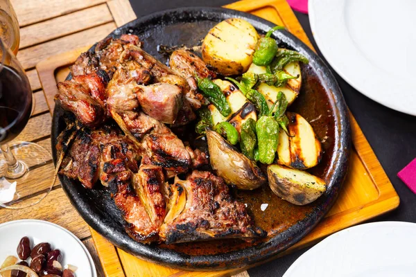 Image of the popular Spanish dish Chuleton of beef steak with bone, served delicious potatoes and pepper in a frying ..pan