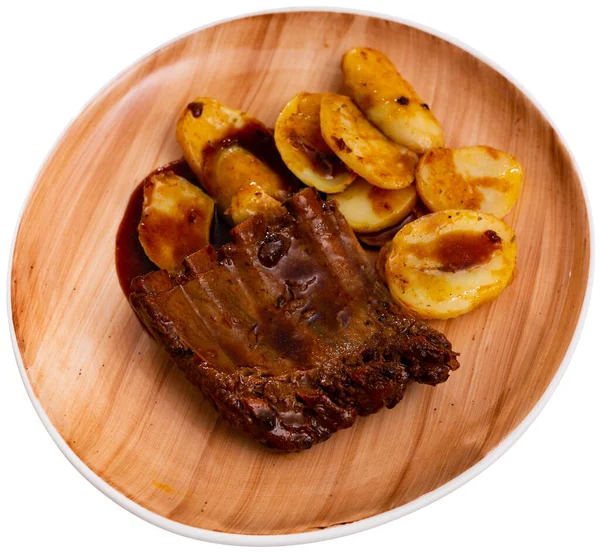 Baked under sauce tasty pork ribs at plate with potatoes. Isolated over white background