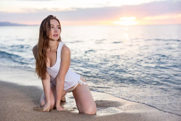 Attractive woman posing in the surf at sunset