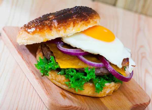 Tasty grilled beef burger for breakfast with cheese, lettuce, onion, fried egg