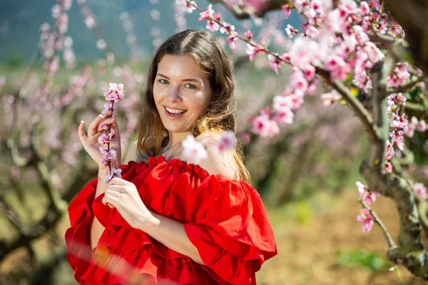 Krásná Usmívající Mladá Američanka Pózující Parku Kvetoucími Květy Broskvoně Stromů — Stock fotografie