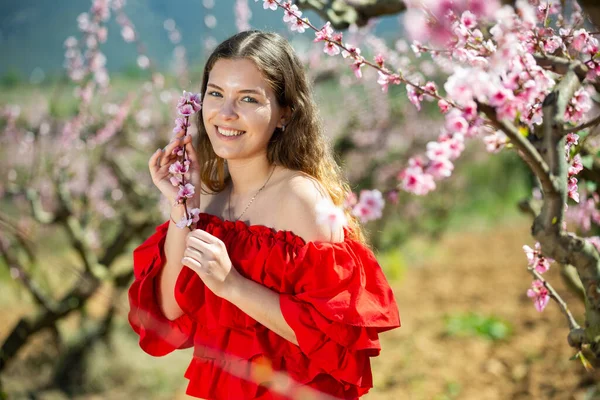 Kırmızı Elbiseyle Poz Veren Neşeli Bir Kız Çiçek Açan Bir — Stok fotoğraf