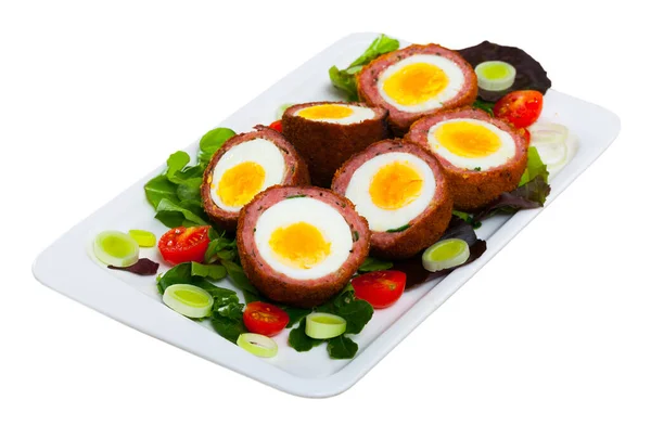 Traditional British picnic food - delicious Scotch eggs cut in halves with vegetable salad of greens and tomatoes. Isolated over white background.