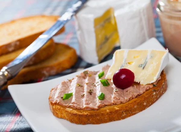 Delicate liver pate served on toasted bread with soft blue cheese and cranberry berry