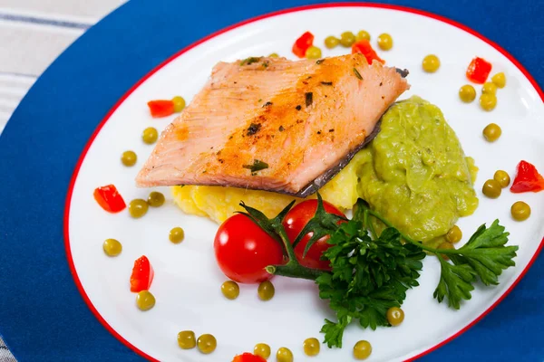 Healthy dinner, grilled trout fillet with potato puree, guacamole, peas and parsley