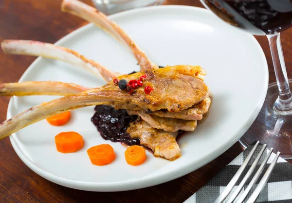 Baked lamb ribs with spicy sauce and carrots served at plate in cafe