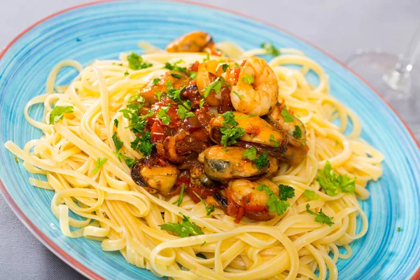 Traditional Italian seafood cuisine. Pasta with shrimps and mussels braised with vegetables and greens