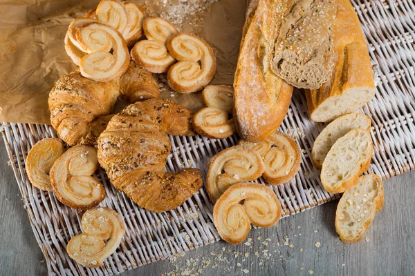 Draufsicht Auf Verschiedene Frische Backwaren Auf Rattanmatte Auf Holztisch — Stockfoto