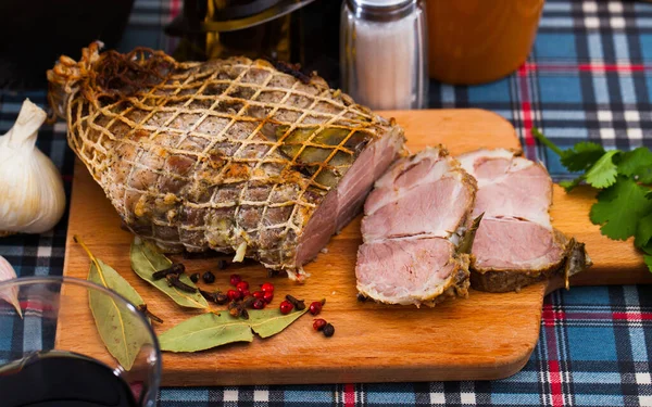 Savory pork baked in oven in large piece server on wooden cutting board..