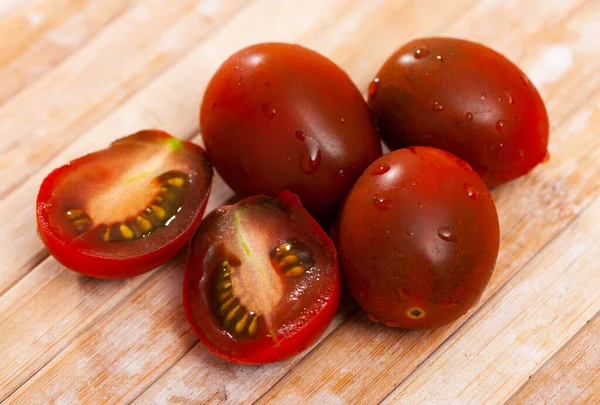 Seluruh Dan Irisan Segar Matang Tomat Mini Kecoklatan Atas Meja — Stok Foto