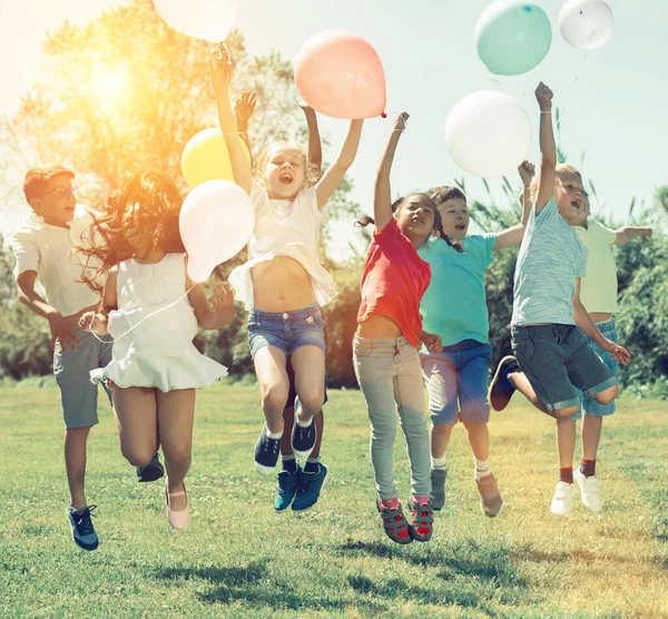 Grupo Niños Felices Sosteniendo Globos Saltando Juntos Parque — Foto de Stock