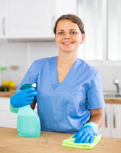 作業服の若い女性の肖像手袋のラグと洗剤でキッチンのカウンタートップを掃除 — ストック写真