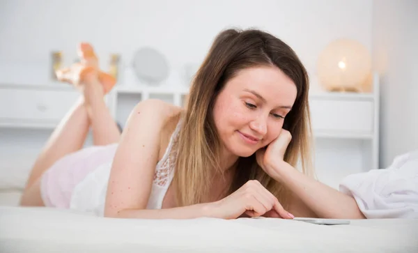 여자가 침대에서 백지에 휴대폰을 사용하는 — 스톡 사진