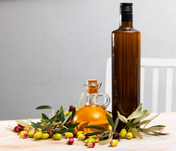 Butelki Szklane Karafki Świeżą Oliwą Drewnianym Stole Gałązkami Oliwnymi Świeżymi — Zdjęcie stockowe