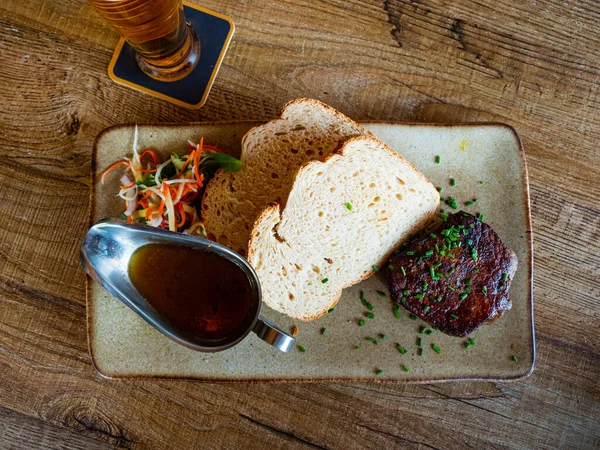 Popular dish of Dutch cuisine is the kogel steak dikbil, decorated with chopped green onions on top, with two sandwiches ..and sauce. Served with beer