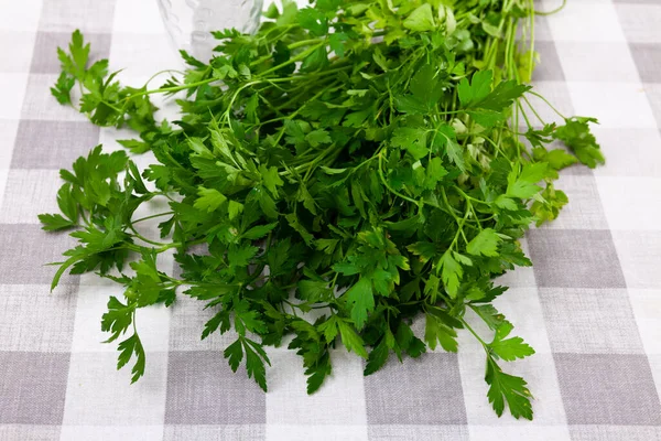 Bundle of organic parsley herbs on checkered tablecloth on kitchen table
