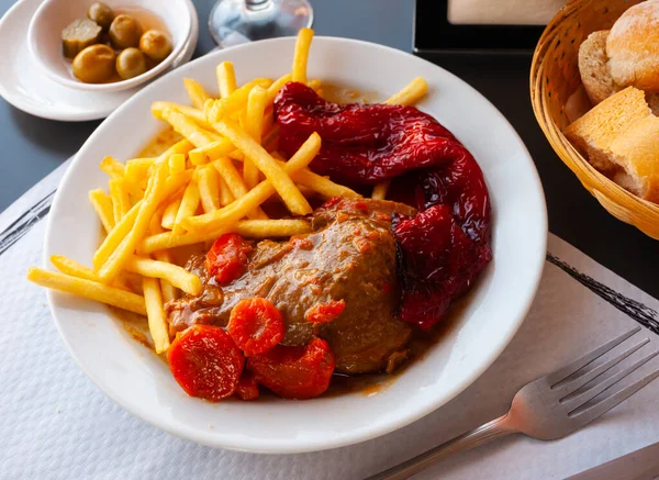Dish of Spanish cuisine - pork cheeks with potatoes fri and stew vegetables. High quality photo