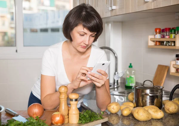 Positiv Hausfrau Texting Auf Sie Gadget Während Cooking Kitchen — Stockfoto