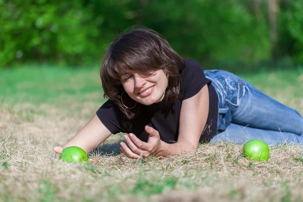 Dark-haired girl with green apples extends a hand — Stock Photo, Image
