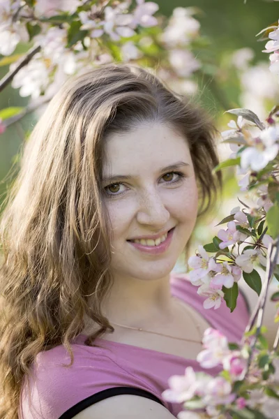 Retrato da jovem mulher contra uma macieira florescente — Fotografia de Stock