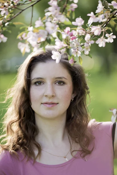 Portret van de jonge vrouw tegen een bloeiende appelboom — Stockfoto