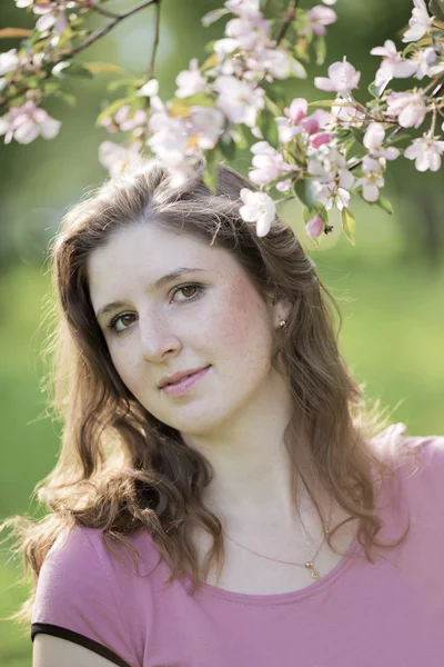 Portret van de jonge vrouw tegen een bloeiende appelboom — Stockfoto