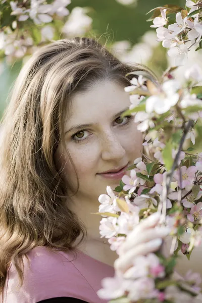 Portret van de jonge vrouw tegen een bloeiende appelboom — Stockfoto