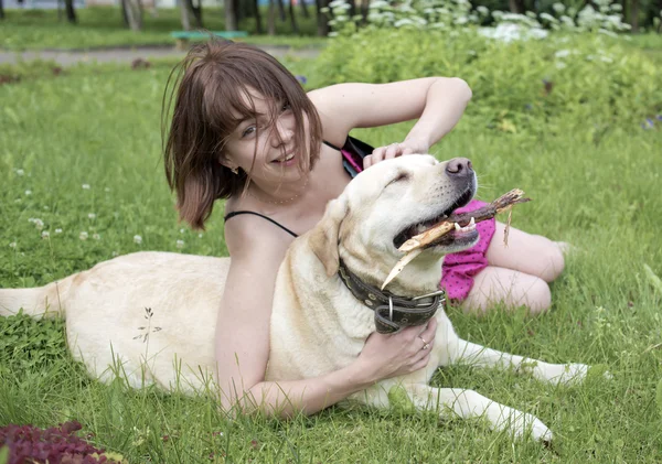 A menina em um gramado brinca com um cão — Fotografia de Stock