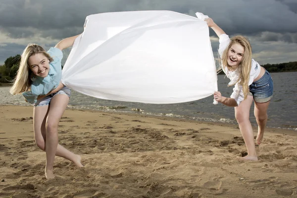 Zwei Mädchen halten einen weißen Stoff in der Hand — Stockfoto