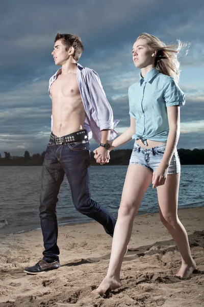 De jongen en het meisje gaan op een strand — Stockfoto
