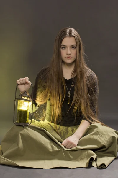 The girl with a lantern sits on a black background — Stock Photo, Image