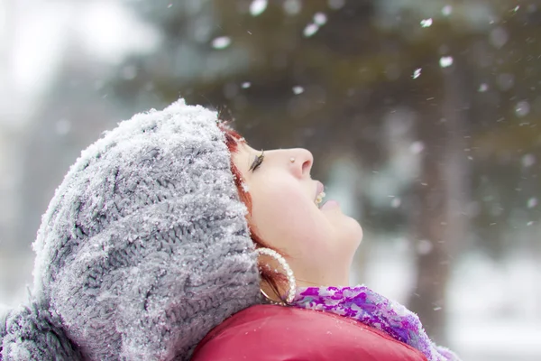 Das junge Mädchen fängt Schneeflocken — Stockfoto