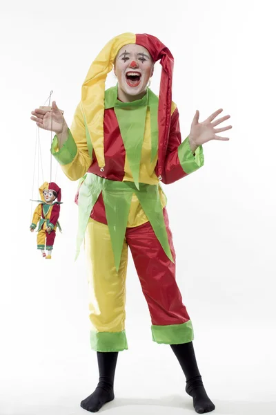 Das Mädchen im Clownanzug hält ein Spielzeug des Clowns in der Hand — Stockfoto