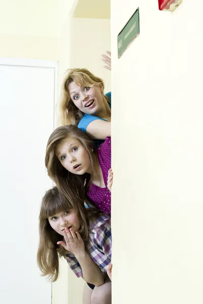 Três curiosos espreitando em torno da porta — Fotografia de Stock