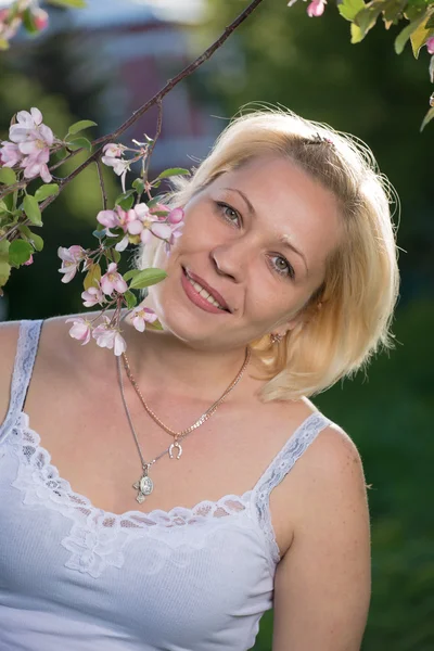 Blond woman in blossom garden — Stock Photo, Image