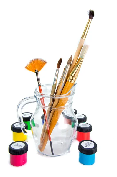 Paintbrushes in glass jug with paints — Stock Photo, Image