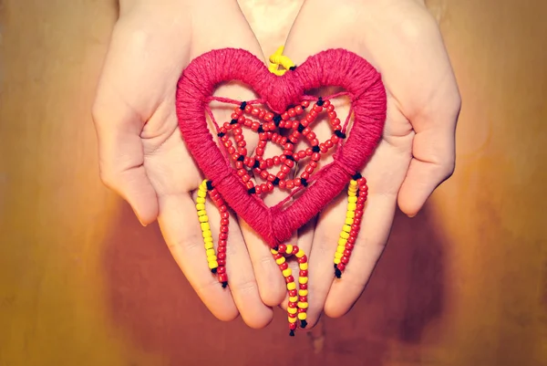 Corazón rojo de cuentas de colores en las manos —  Fotos de Stock