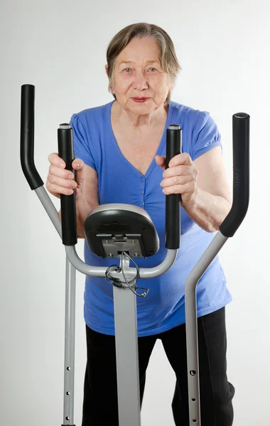 Mujer mayor en bicicleta de entrenamiento estacionario — Foto de Stock