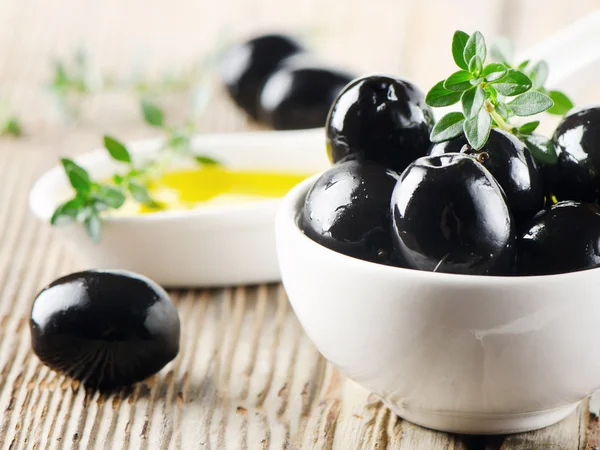 Zwarte olijven op een houten tafel — Stockfoto