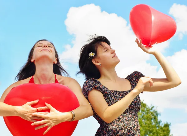 Young women holding red balloons against sky — Stock Photo, Image