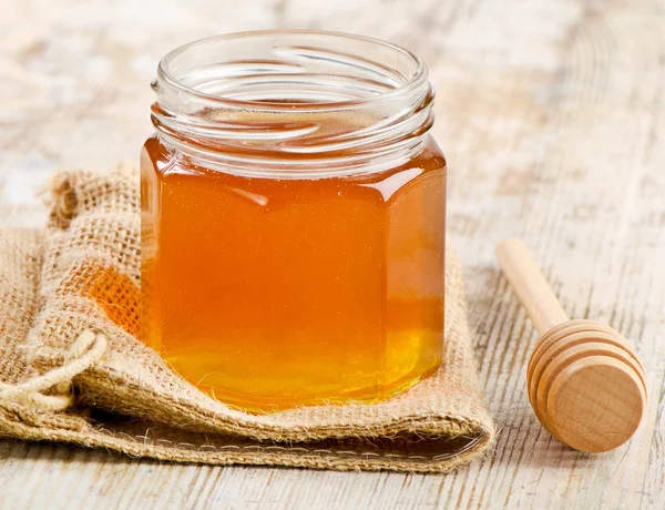 Jar of honey with wooden stick — Stock Photo, Image