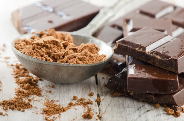 Cacao en polvo y barra de chocolate roto y en una mesa de madera — Foto de Stock