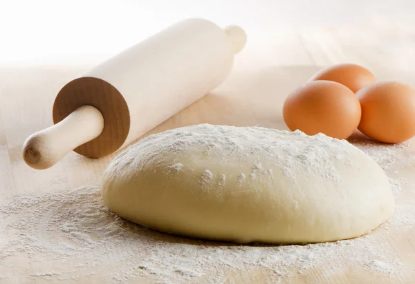 Dough with rolling pin on wooden table — Stock Photo, Image