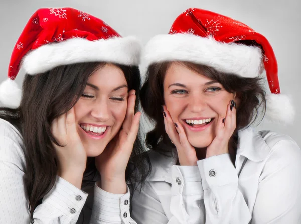 Молодые счастливые улыбающиеся девушки в шляпах Санты — стоковое фото