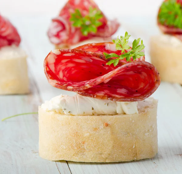 Baguette with salami and cream cheese with herbs. — Stock Photo, Image