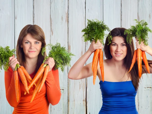 Jóvenes mujeres sonrientes sostiene racimo de zanahorias — Foto de Stock