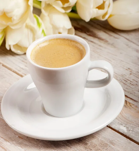 Coffee cup a bílé tulipány — Stock fotografie