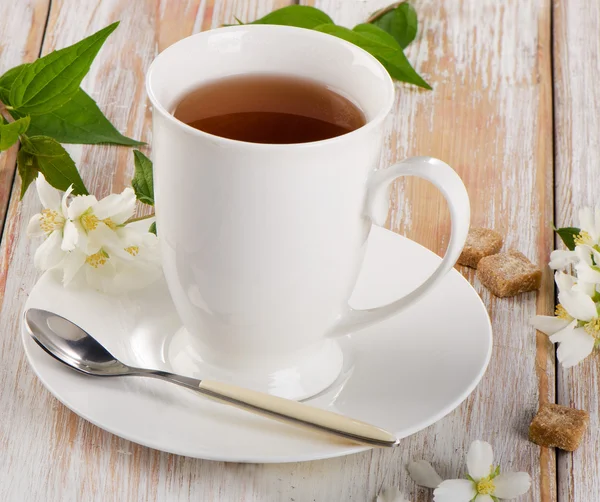 Thé dans une tasse blanche avec des fleurs — Photo